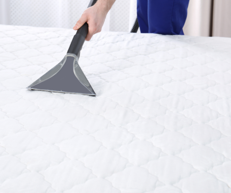 Hand pushing a vacuum on a white mattress