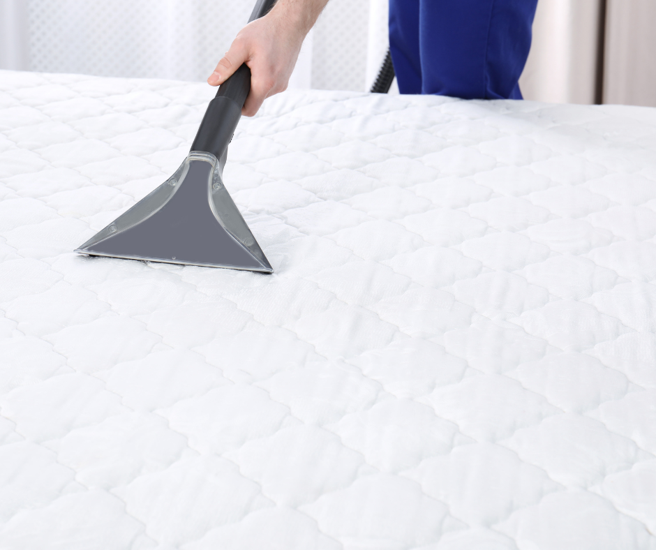 Hand pushing a vacuum on a white mattress